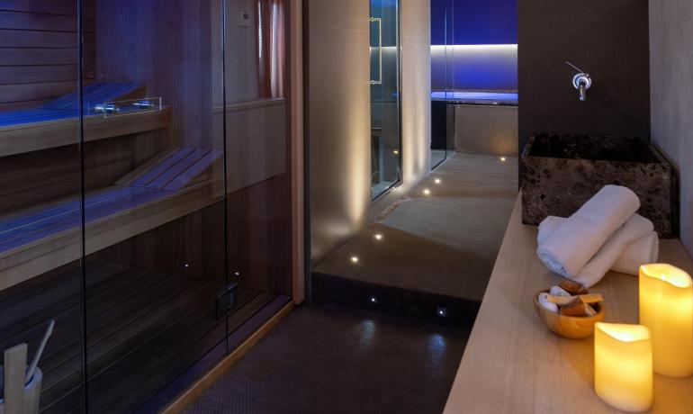 Spa elegante con sauna, luci soffuse e candele per un relax totale.