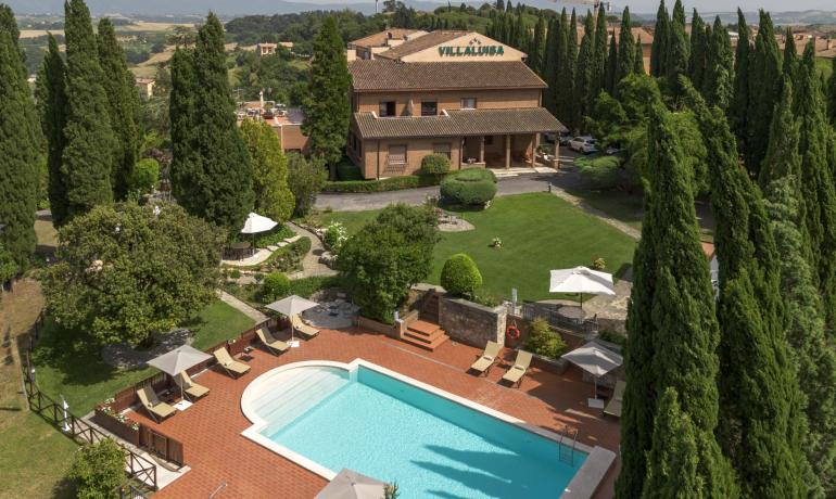 Piscina circondata da cipressi e verde, atmosfera rilassante e accogliente.