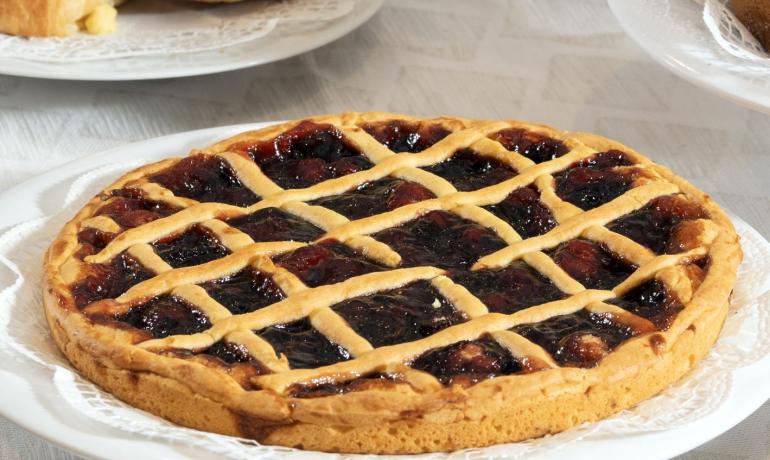 Colazione ricca: crostata, cornetti e frutta fresca su una tavola invitante.