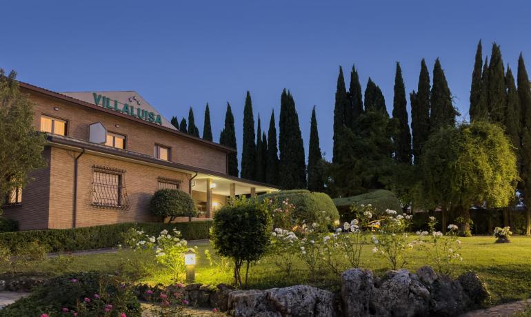 Villa immersa nel verde, atmosfera serena e accogliente al tramonto.